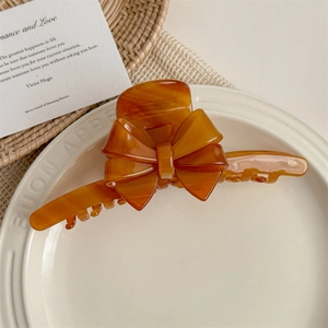Detailed view of large amber bow hair claw clip made of high-quality polished acetate