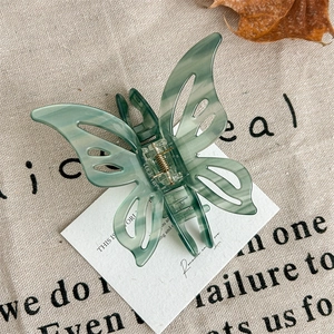 Detail view of green marble butterfly hair claw clip with golden spring on rustic burlap
