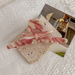 Detail of pink marble acetate hair claw with handmade logo on beige travertine stone