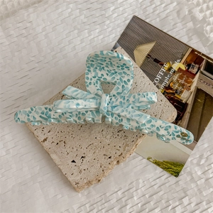 Close-up of blue and white stone pattern acetate hair claw clip with golden Handmade text