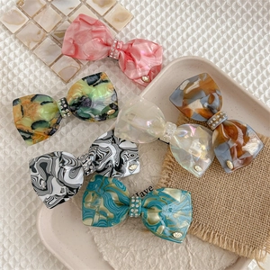 Elegant acetate bow hair clips set with sparkling rhinestones in various marble patterns