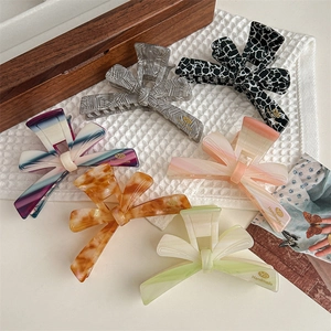 Pink bow acetate hair claw clips in various colors displayed on a white textured towel
