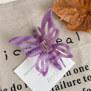 Detail of purple translucent butterfly hair claw clip with golden metal spring on rustic linen