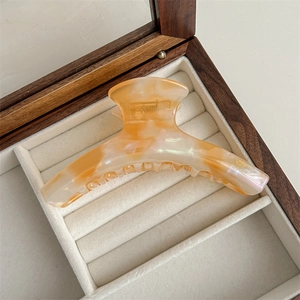 Detail of large acetate hair claw clip with amber texture in a wooden jewelry box