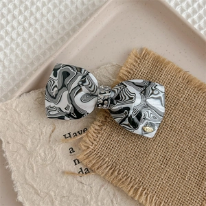 Detail of luxury marble bow hair clip with sparkling rhinestones and acetate texture