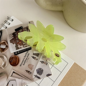 Gros plan d'une pince à cheveux fleur vert néon sur un fond de magazine vintage