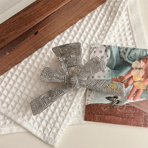 Detail of large butterfly hair claw with grey stripes on a white textured towel background