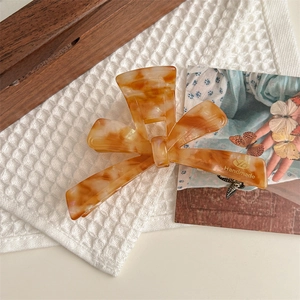 Macro detail of large amber marble hair claw clip with golden handmade logo on waffle towel