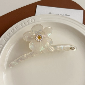 Détail macro de la pince à cheveux fleur en acétate nacré avec un petit motif de marguerite