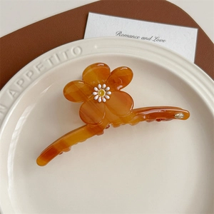 Détail de la pince à cheveux fleur ambre avec motif marguerite sur un plat blanc