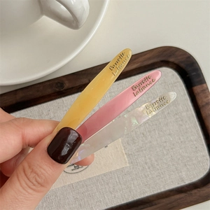 Three-piece acetate hair clip set in yellow pink and white with gold lettering