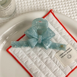 Macro detail of handmade light blue striped bow hair claw clip in high gloss acetate