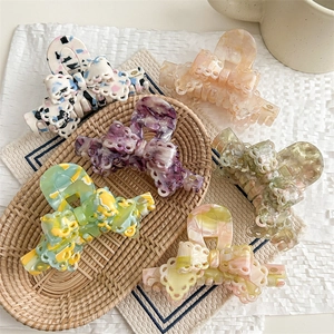Lace bow hair claws in various colors set in a woven basket with marble finish