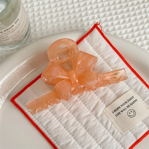 Detail of peach pink handmade acetate bow hair claw clip with marble texture