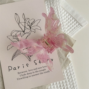 Détail d'une pince à cheveux papillon rose pailletée sur une carte à fleurs