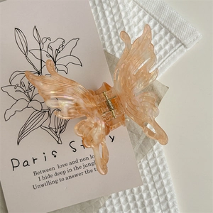 Gros plan d'une pince à cheveux papillon rose nacré avec de fins accents pailletés