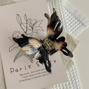 Gros plan sur une pince à cheveux papillon avec motif écaille et détails ajourés