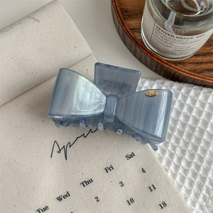 Dettaglio della pinza per capelli a fiocco blu elegante con logo dorato di lusso