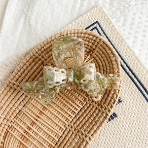 Detail of floral acetate hair claw with gold Handmade logo in a rustic wicker basket