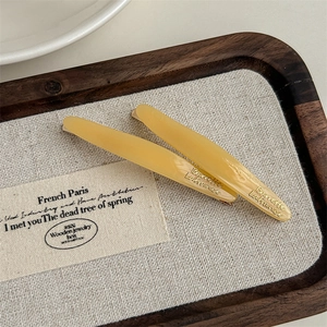 Close-up of elegant pale yellow acetate hair clips with engraved Barrette LaFrance text