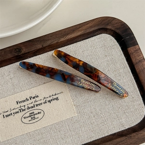 Detailed close-up of tortoise shell acetate hair clips with gold foil lettering