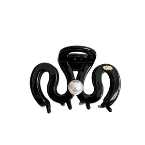 Glossy black hair claw clip with a white pearl and YD gold metal emblem on white background