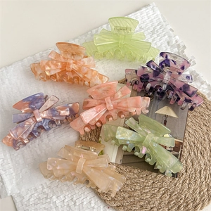 Set of seven colorful marble texture acetate bow hair claws on a minimalist background