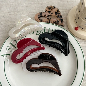 Elegant acetate heart hair claw clips in pearl white and tortoiseshell on a ceramic plate
