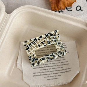 Detail of a rectangular hair claw clip with black and white checkered mosaic pattern
