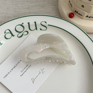 French acetate heart hair claw clip with pearlescent finish on elegant porcelain dish