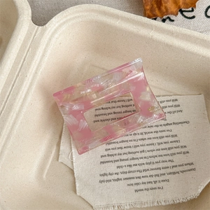 Macro detail of a pink marble acetate hair claw clip showing smooth texture and handmade text