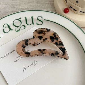 Close-up of heart-shaped tortoiseshell hair claw clip with acetate finish and gold accent