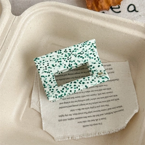 Detail view of square hair claw clip with vintage green polka dots and handmade gold label