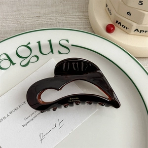 Close-up of chocolate brown heart acetate hair claw with golden Barrette La France text