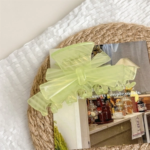 Detailed top view of a lime green acetate butterfly hair claw clip on a woven mat