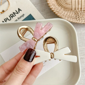 Elegant bow-shaped metal hair claws in pink marble and white with gold finish