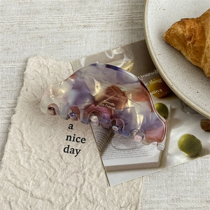 Detail of a purple marble acetate hair claw clip with golden Barrette La France logo