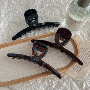 Three large French hair claws in black, coffee, and tortoise shell on a wooden tray