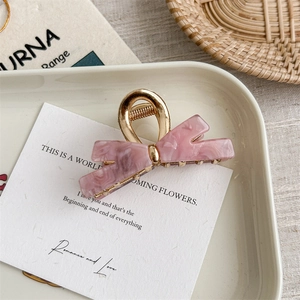 Close-up of pink marble pattern bow hair claw with elegant gold metal mechanism
