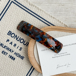 Macro detail of French handmade tortoise shell acetate hair clip on rustic fabric