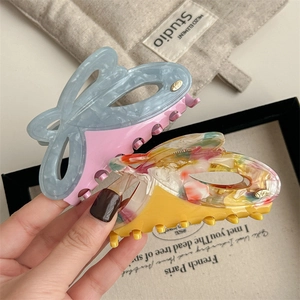Elegant large acetate hair claws with marble and floral patterns in two-tone colors