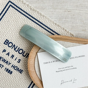 Detail view of a celadon acetate hair clip with gold France Handmade logo