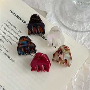 Set of 5 elegant acetate hair claws in various colors on vintage book pages background