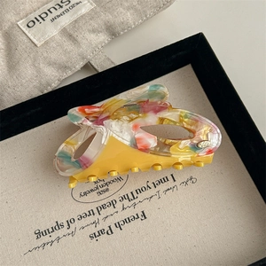Detailed close-up of a high-quality acetate hair claw clip with floral patterns and a gold YD logo