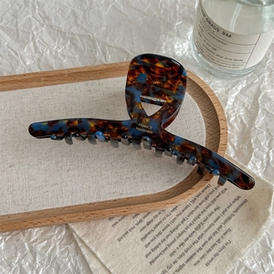 Detail showing the brown and blue tortoiseshell large hair claw with gold logo