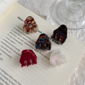 Elegant acetate mini hair clips in various patterns on a vintage book setting