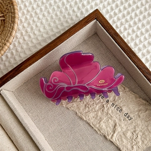 Detailansicht der lila Harz Schmetterling Haarklammer mit goldenem YD Handmade Logo