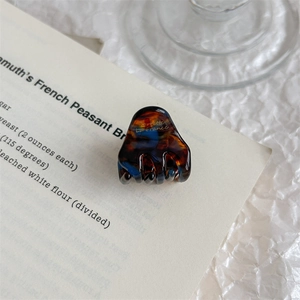 Detail of elegant tortoiseshell hair claw clip featuring marble texture and logo