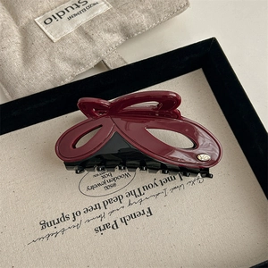 Macro shot of bicolored acetate hair claw clip with metallic logo in burgundy and black