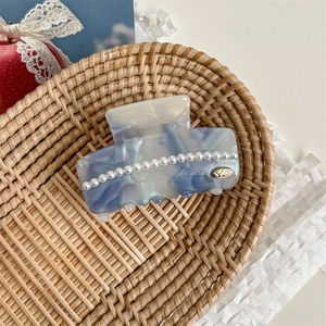 Macro shot of large acetate shark clip with blue marble pattern and inlaid pearls